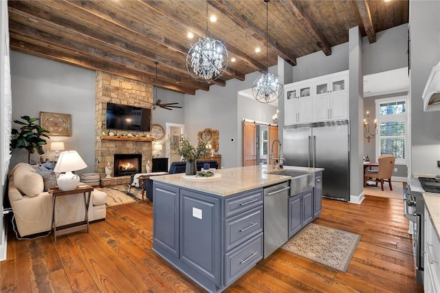 kitchen with dark wood-style floors, a fireplace, stainless steel appliances, open floor plan, and white cabinetry