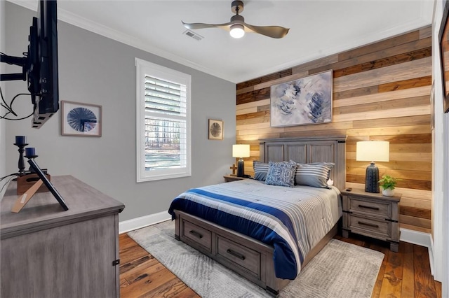 bedroom featuring crown molding, dark wood finished floors, visible vents, wood walls, and baseboards