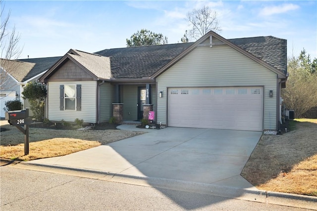 view of front of house with a shingled roof, driveway, an attached garage, and central AC unit