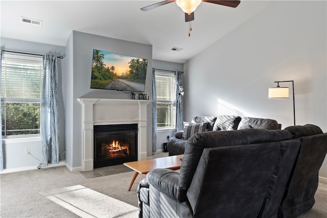 living area with carpet floors, a glass covered fireplace, visible vents, and baseboards