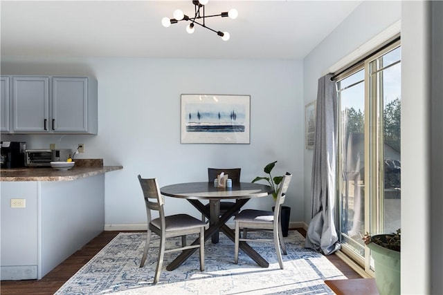 dining area with a notable chandelier, baseboards, and dark wood-style flooring