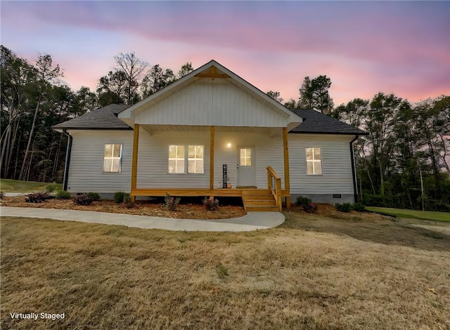 rear view of property with crawl space, covered porch, a shingled roof, and a yard