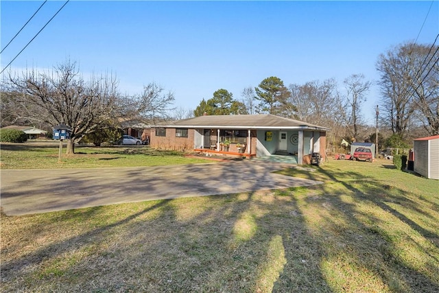 view of front of property featuring a front yard, covered porch, and driveway