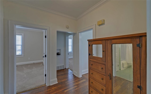 hall featuring a wealth of natural light, ornamental molding, dark wood finished floors, and visible vents