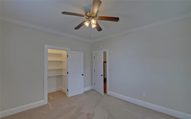 unfurnished bedroom featuring ornamental molding, baseboards, a walk in closet, and light colored carpet