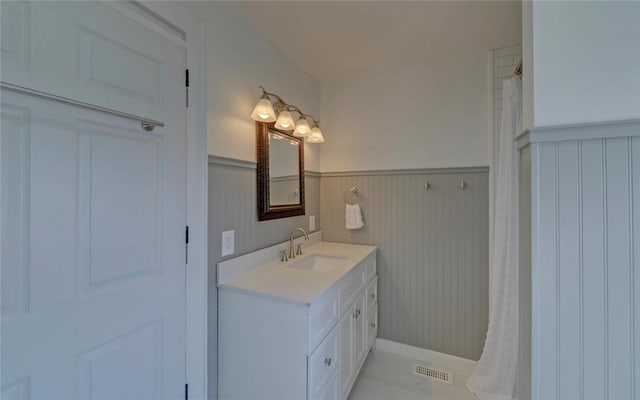 bathroom with a wainscoted wall, visible vents, and vanity