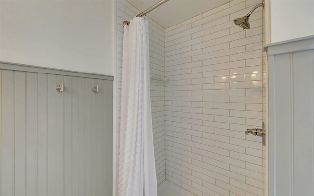 full bathroom with a shower stall and wainscoting