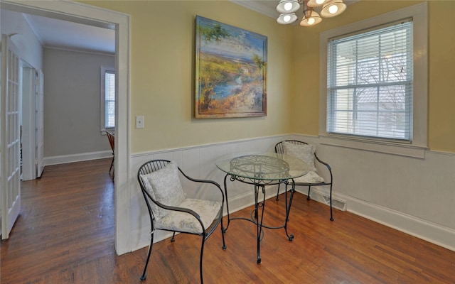 dining room with wainscoting, a notable chandelier, crown molding, and wood finished floors