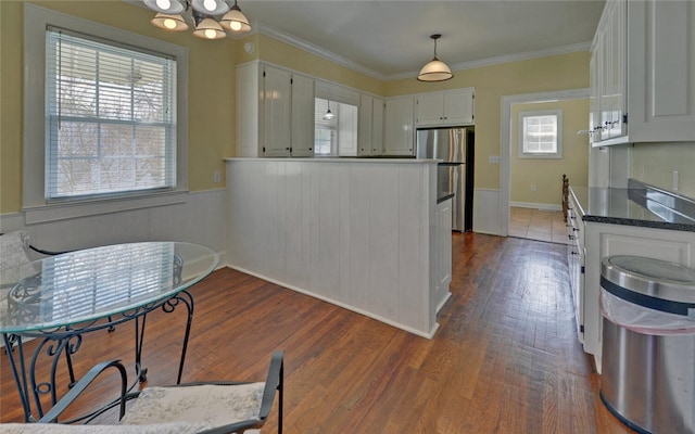 kitchen with a peninsula, white cabinetry, ornamental molding, freestanding refrigerator, and dark wood-style floors