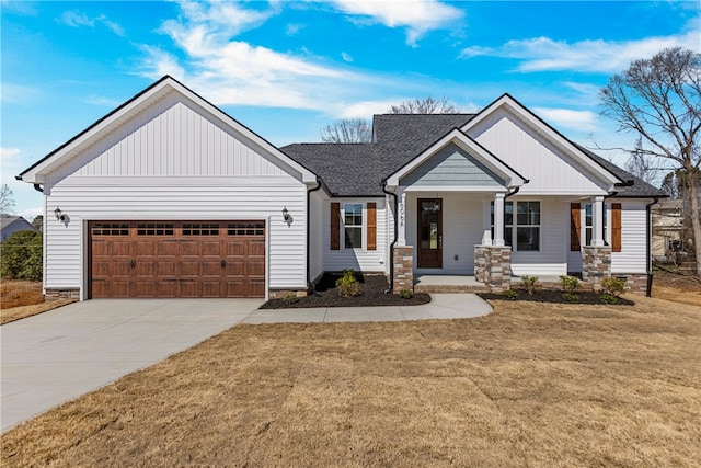 view of front facade featuring a garage, a front yard, roof with shingles, and driveway