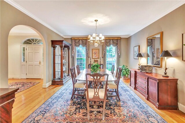 dining room with baseboards, light wood-style floors, crown molding, and an inviting chandelier