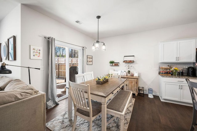 dining room with dark wood-style floors, baseboards, visible vents, and a notable chandelier