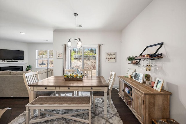 dining space with an inviting chandelier, a fireplace, and dark wood finished floors