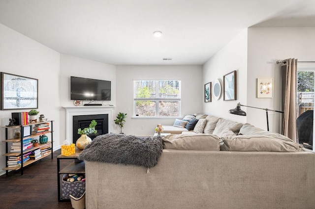 living room with dark wood-style flooring, plenty of natural light, a glass covered fireplace, and visible vents