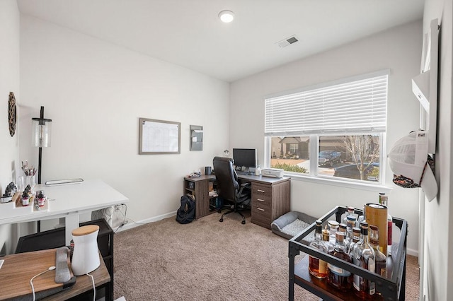 office space featuring baseboards, visible vents, and light colored carpet