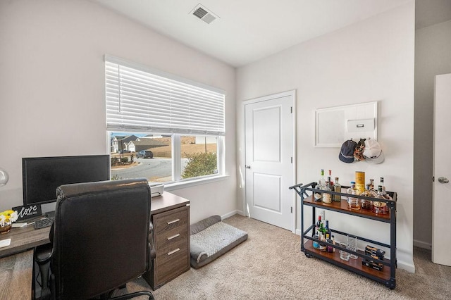 home office featuring baseboards, visible vents, and light colored carpet