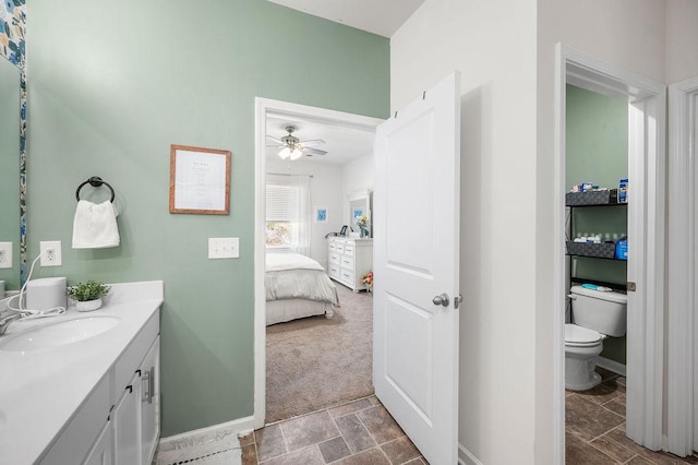 bathroom with baseboards, toilet, vanity, and ensuite bath