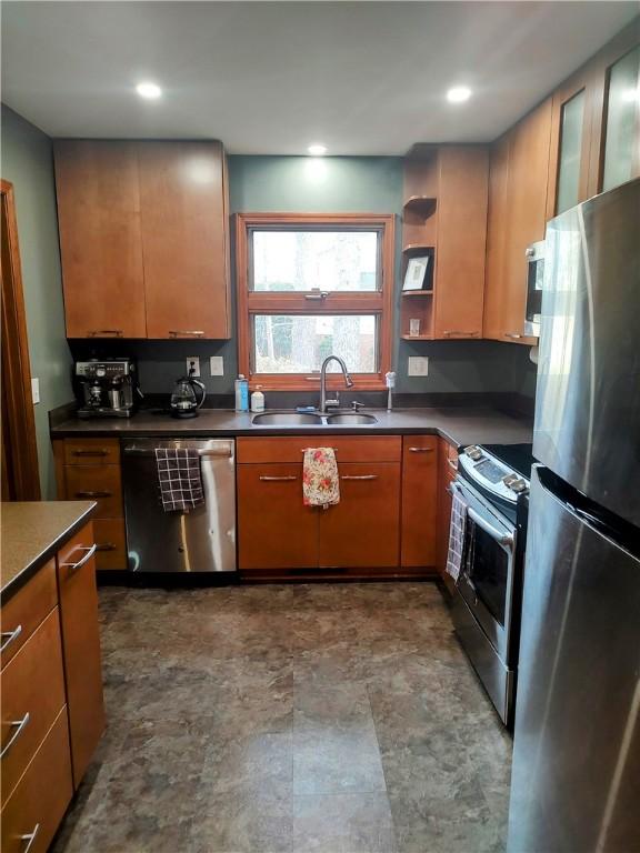 kitchen featuring open shelves, stainless steel appliances, dark countertops, recessed lighting, and a sink