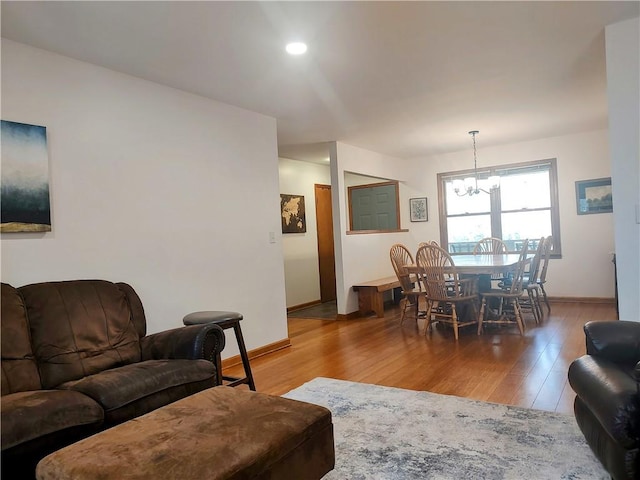 living room featuring an inviting chandelier, baseboards, wood finished floors, and recessed lighting