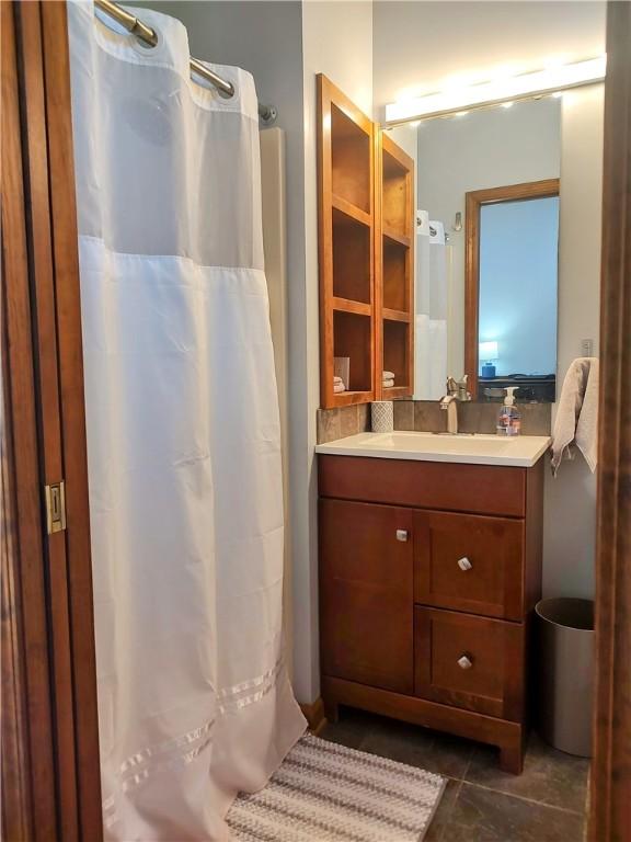 full bath with a shower with shower curtain, vanity, and tile patterned floors