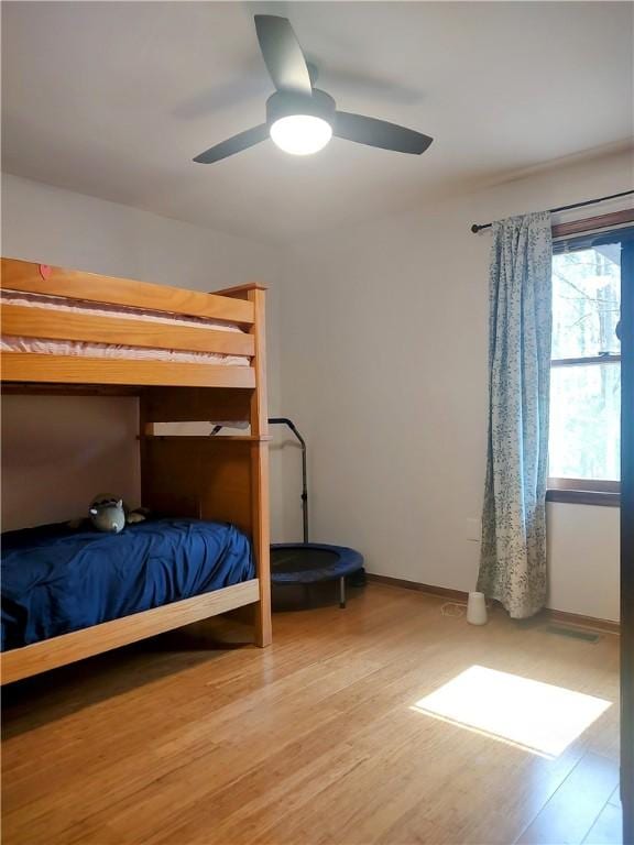 bedroom with ceiling fan, baseboards, and wood finished floors