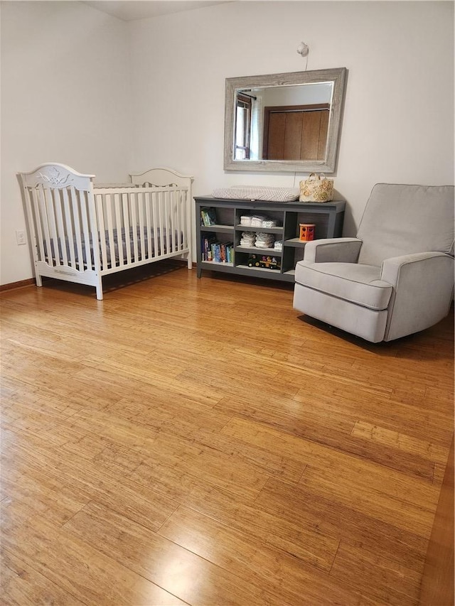 bedroom with a crib, baseboards, and wood finished floors