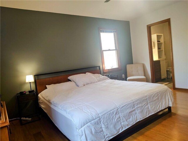 bedroom featuring wood finished floors and connected bathroom