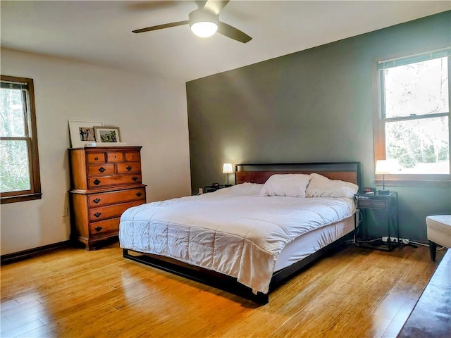 bedroom with multiple windows, ceiling fan, light wood-style flooring, and baseboards