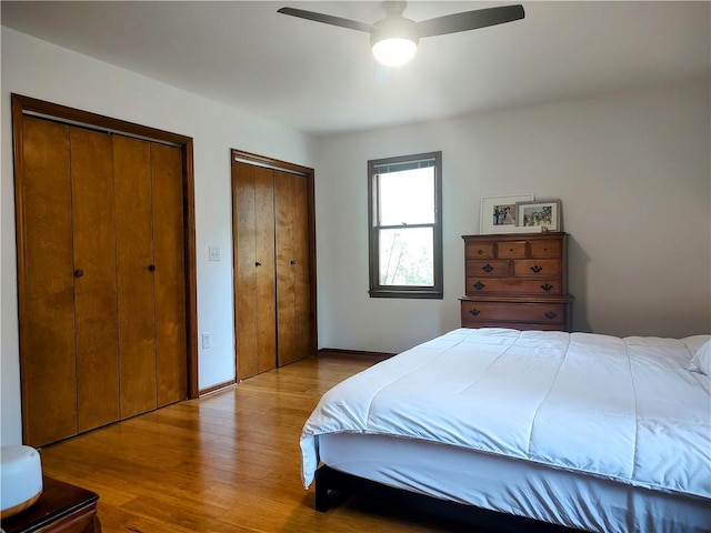 bedroom featuring a ceiling fan, two closets, and wood finished floors