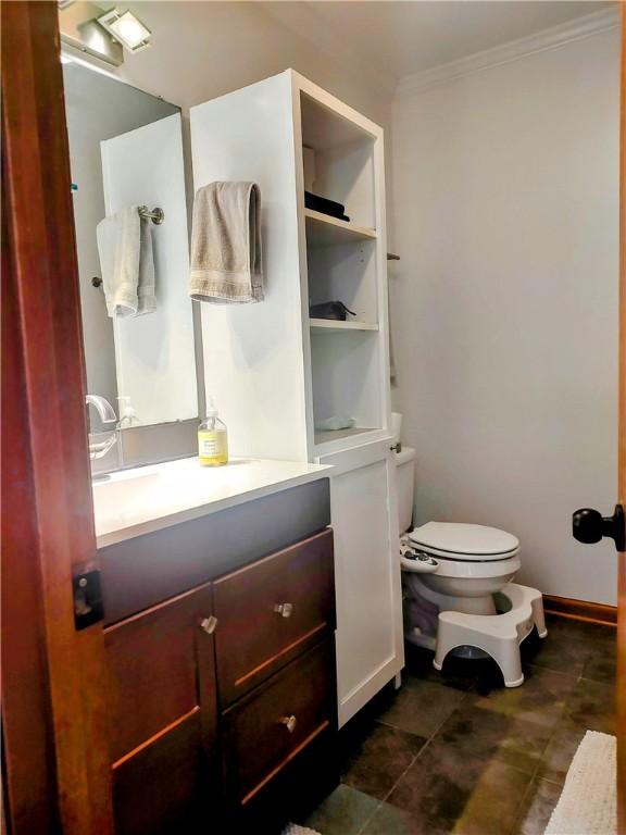 bathroom with toilet, baseboards, crown molding, and vanity