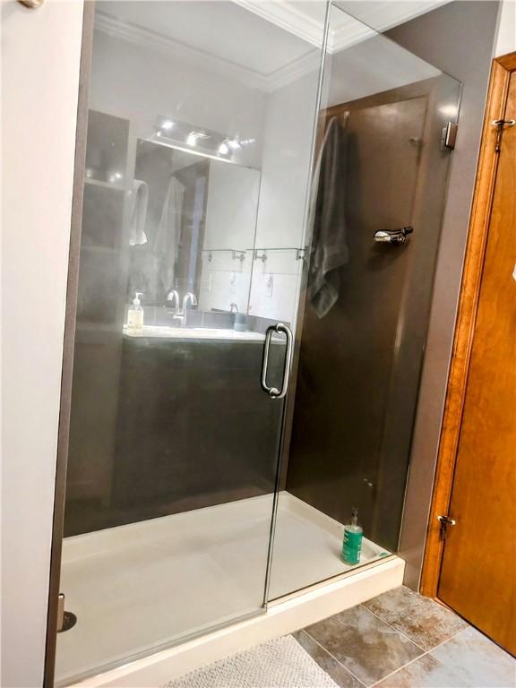 full bathroom featuring tile patterned flooring, a shower stall, and crown molding