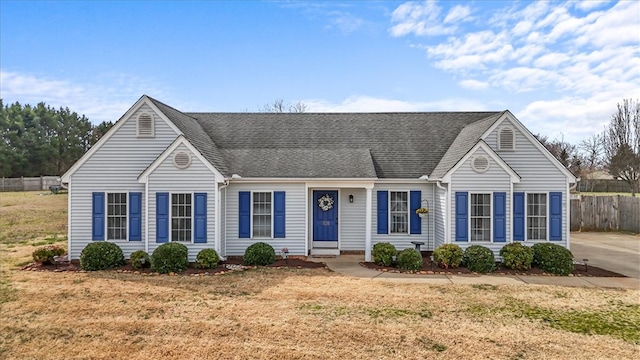 view of front of house with a shingled roof, fence, and a front yard