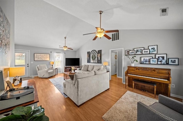 living area with visible vents, vaulted ceiling, and wood finished floors