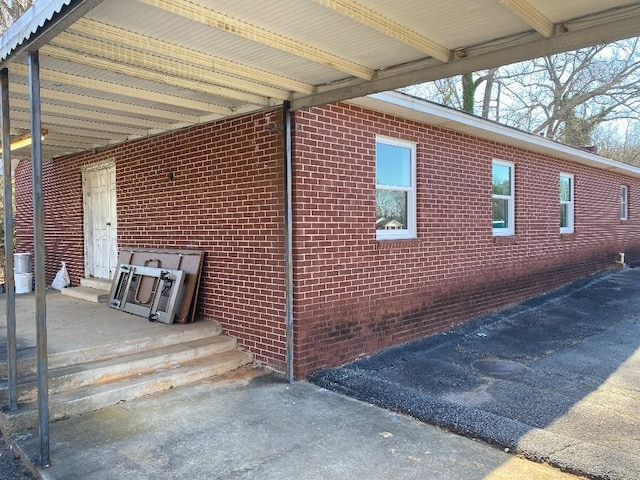 view of home's exterior with driveway, an attached carport, and brick siding