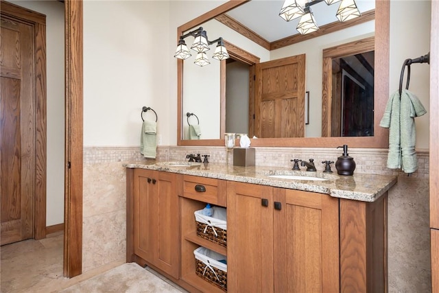 bathroom featuring wainscoting, a sink, tile walls, and double vanity