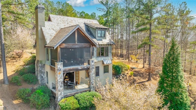 rear view of property with a chimney and stucco siding