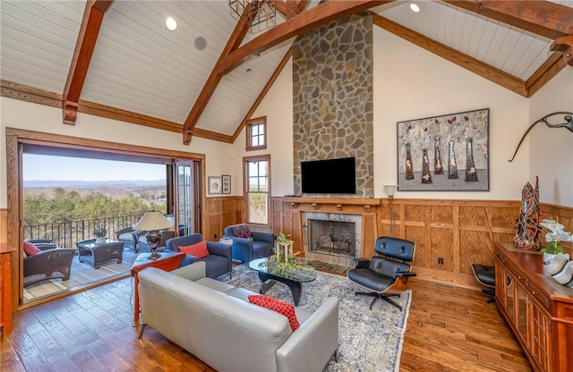 living area with beam ceiling, a wainscoted wall, a fireplace, wood ceiling, and hardwood / wood-style floors