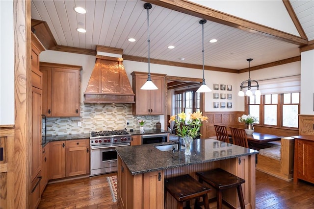 kitchen with wainscoting, ornamental molding, high end stainless steel range, premium range hood, and a sink