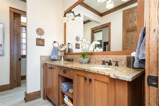 bathroom with a sink, backsplash, baseboards, and double vanity