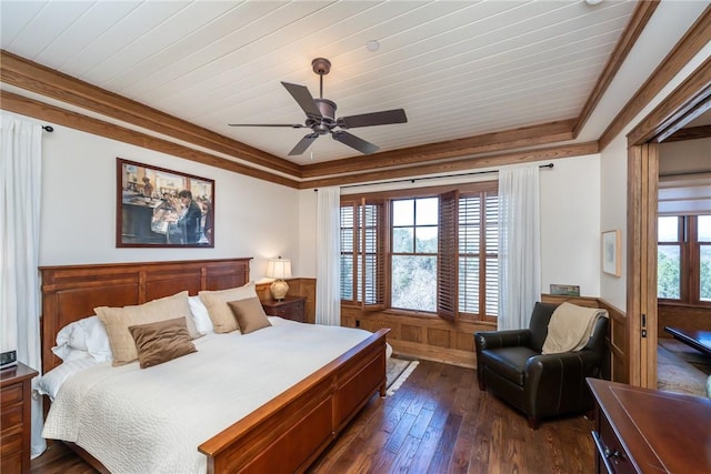 bedroom featuring dark wood-type flooring, a tray ceiling, multiple windows, and crown molding