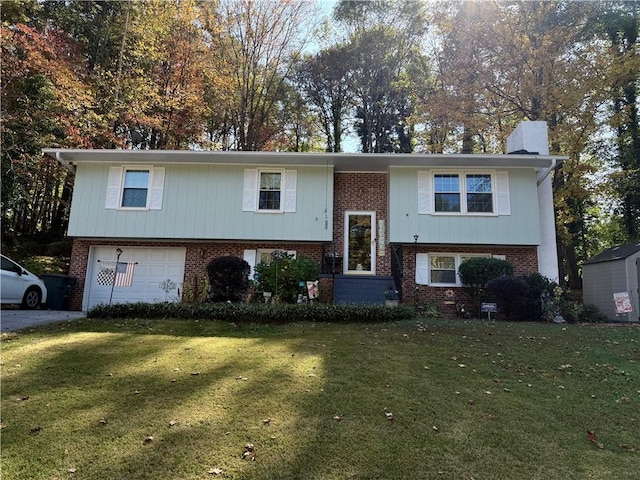 split foyer home featuring an attached garage, a chimney, a front lawn, and brick siding