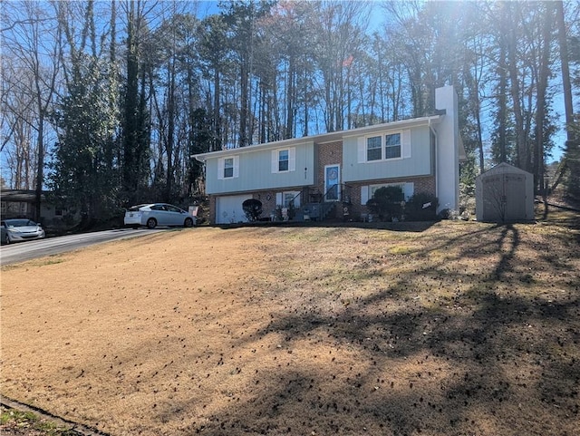 split foyer home with an outbuilding, brick siding, a chimney, a storage shed, and driveway