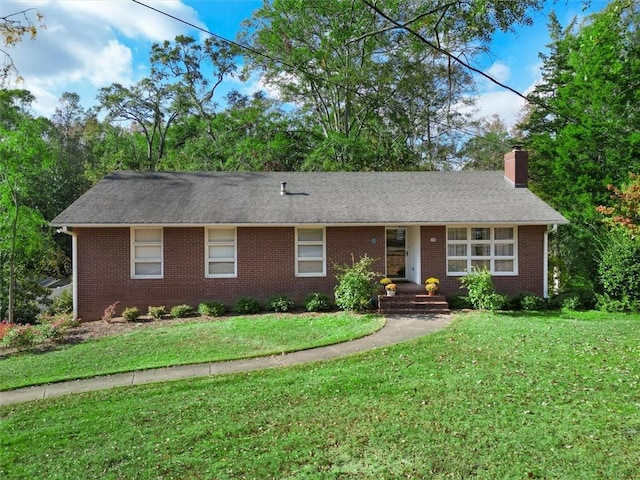 ranch-style house featuring a front lawn, a chimney, a shingled roof, and brick siding