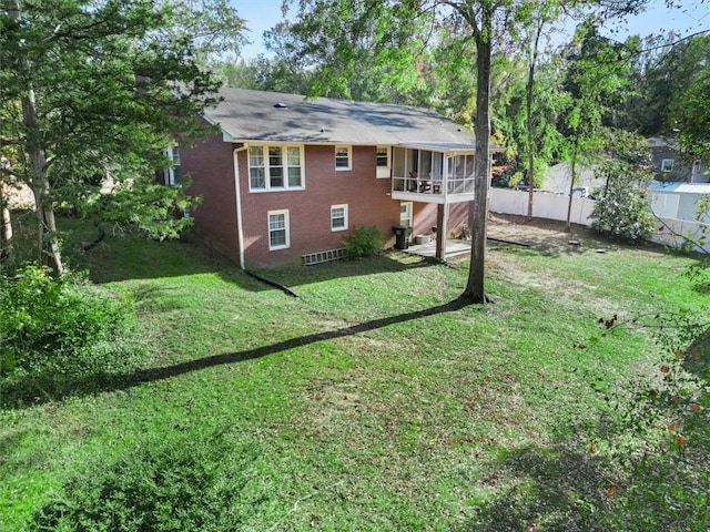 rear view of property with a yard, a sunroom, brick siding, and fence