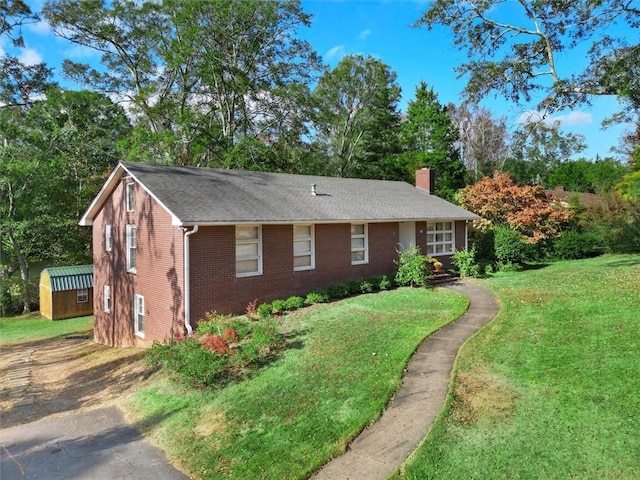 single story home featuring brick siding, a chimney, and a front lawn