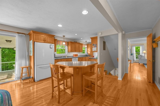 kitchen featuring white appliances, a kitchen breakfast bar, light wood-style floors, brown cabinets, and decorative light fixtures