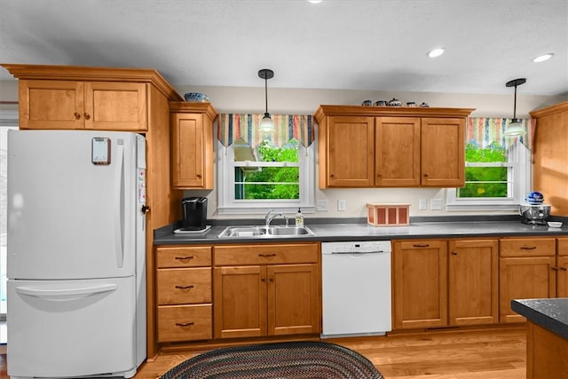 kitchen with dark countertops, white appliances, a healthy amount of sunlight, and a sink