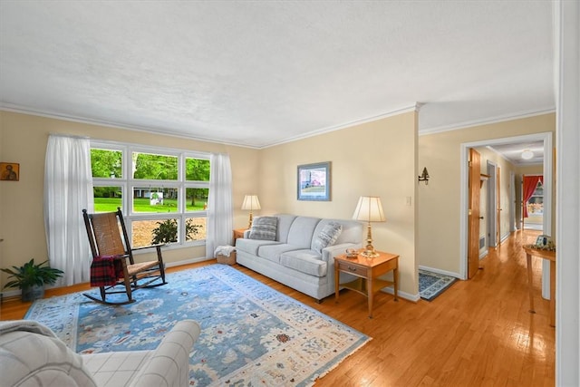 living area featuring light wood-type flooring, baseboards, and crown molding