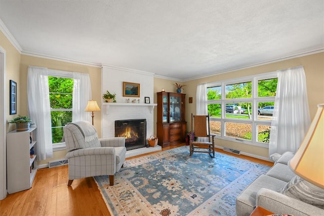 living room featuring ornamental molding, a fireplace, visible vents, and light wood-style floors