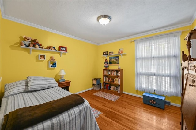 bedroom with baseboards, a textured ceiling, ornamental molding, and wood finished floors